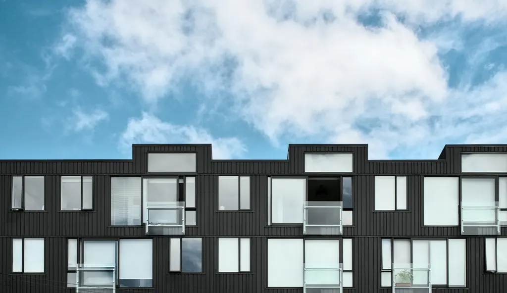 A block of identical apartment units under a blue sky