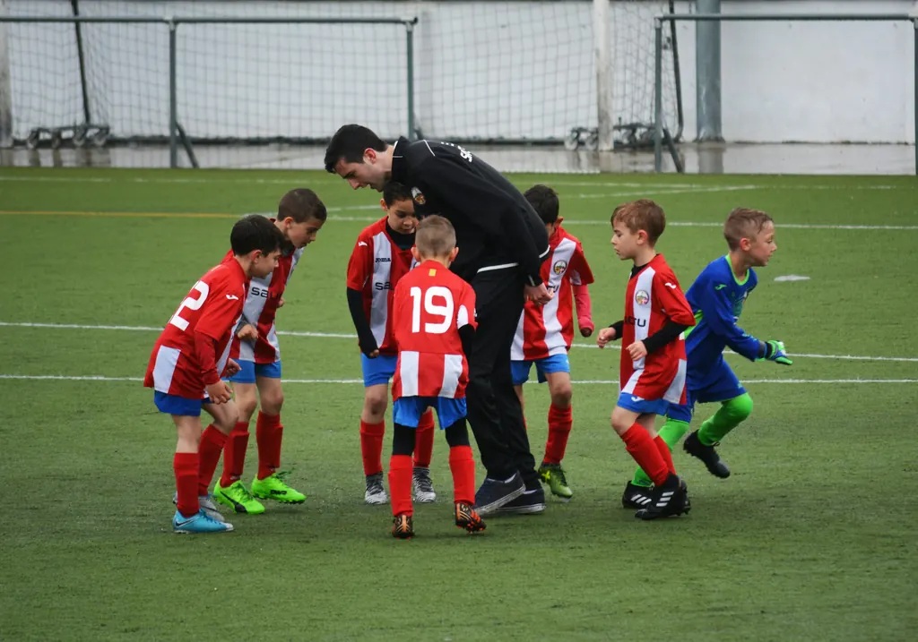 A coach talking to young footballers in a huddle