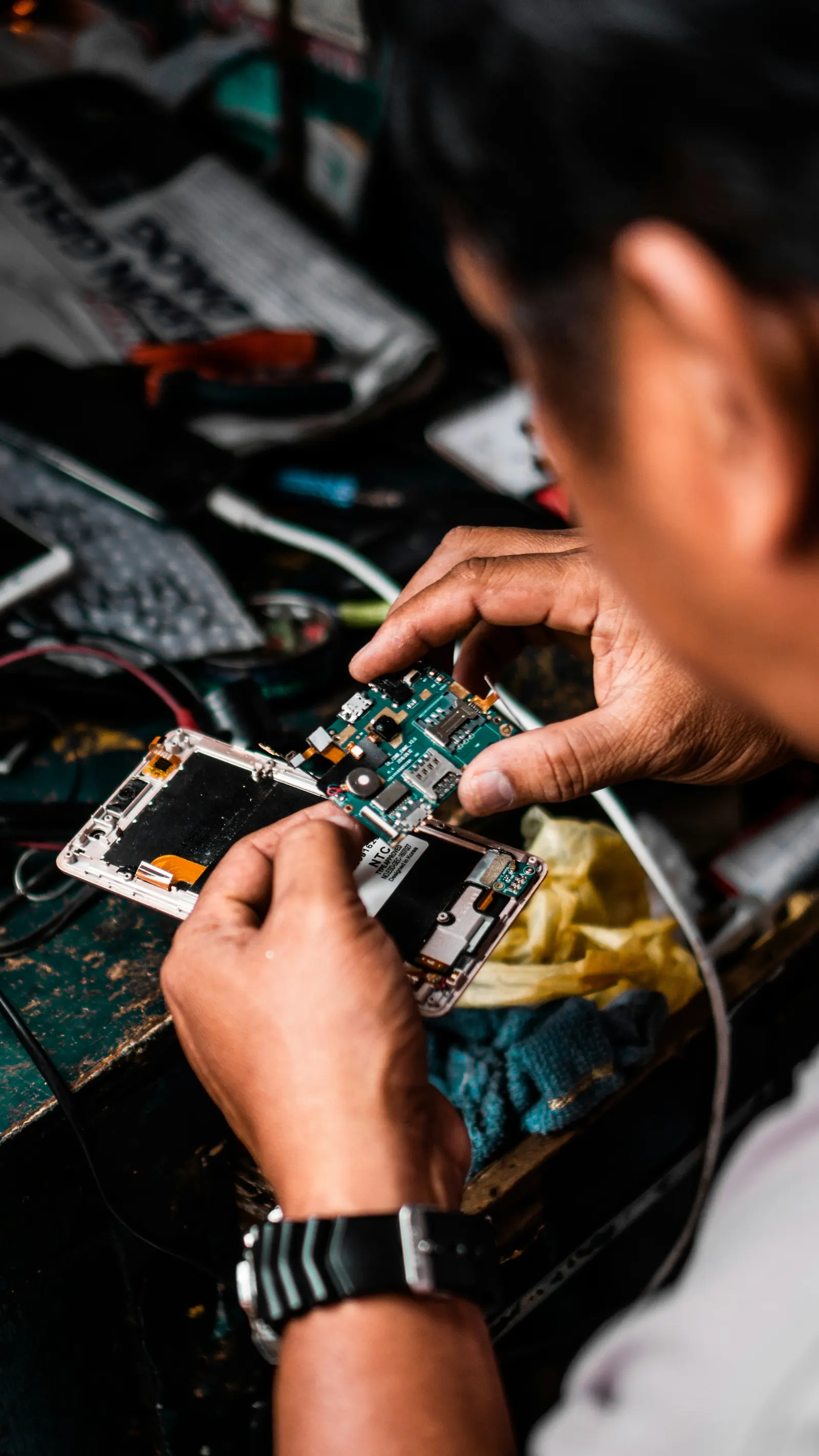 Hands repairing the circuit board of a smartphone