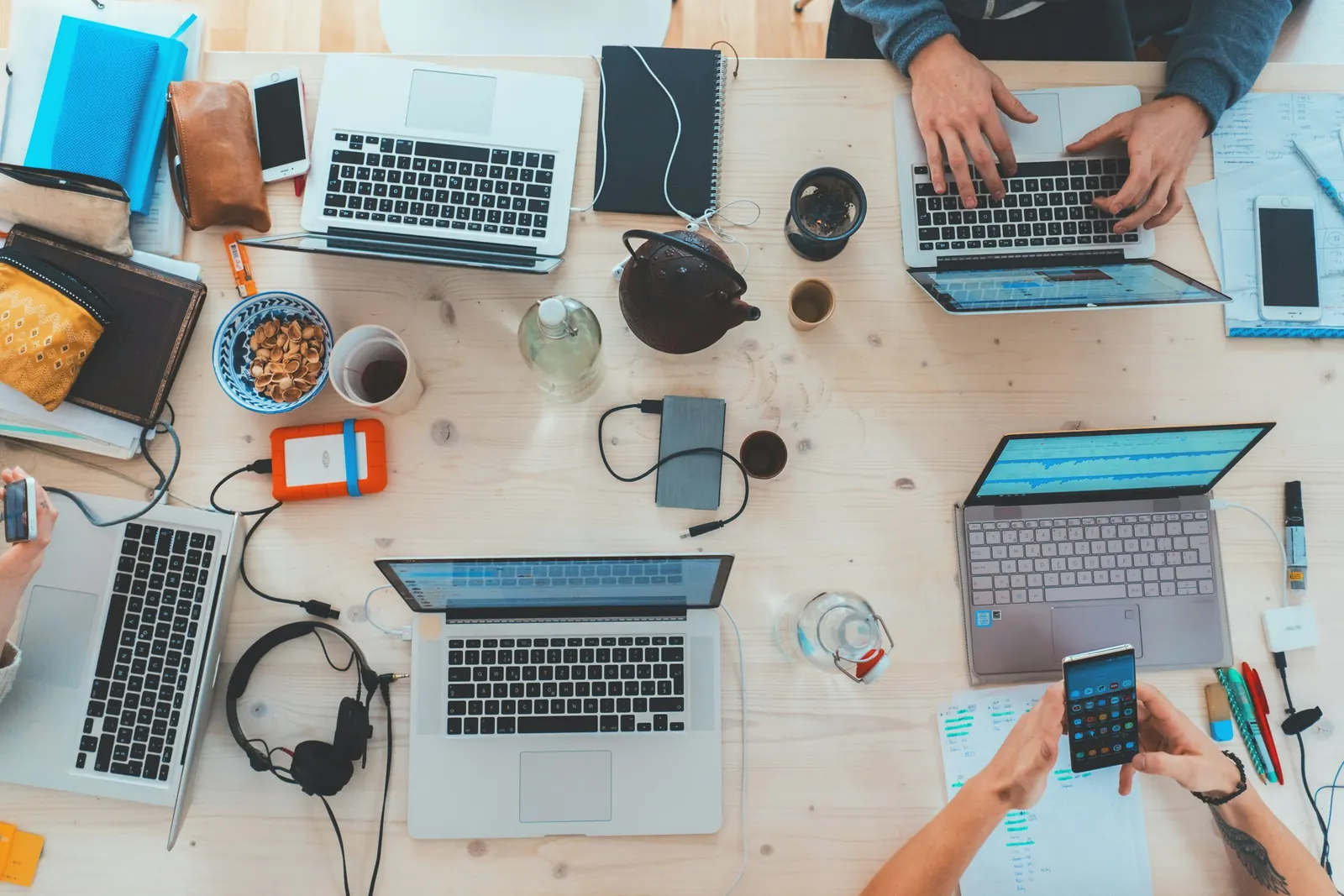 People working on laptops around a shared table, seen from above