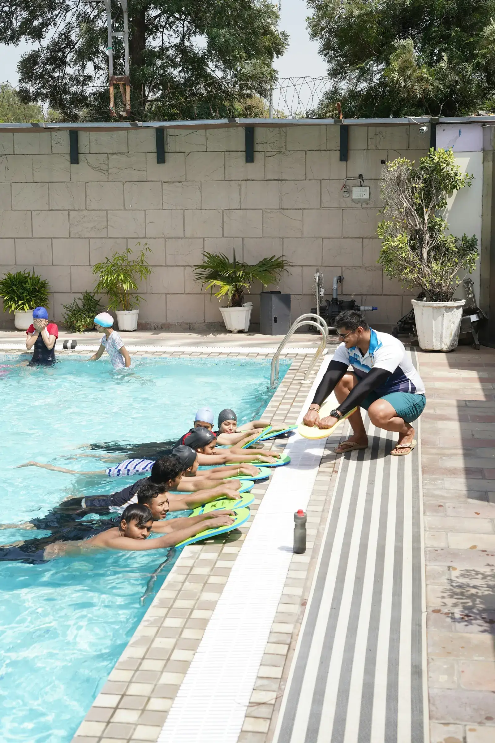 A swimming instructor teaching children with kickboards in a pool